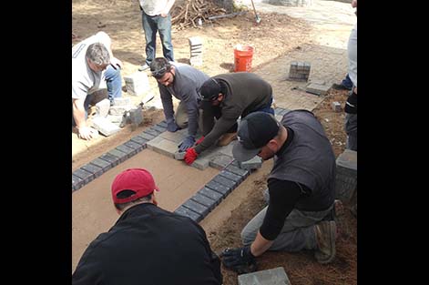 Landscaping students lay stones in a new walkway