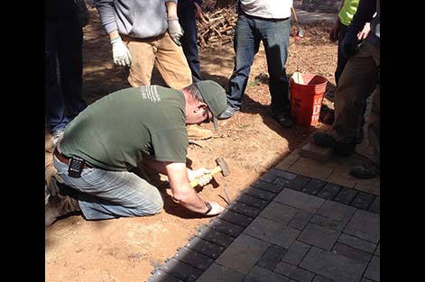 Instructor Alex Burke shows students how to install edging along a new paver walkway