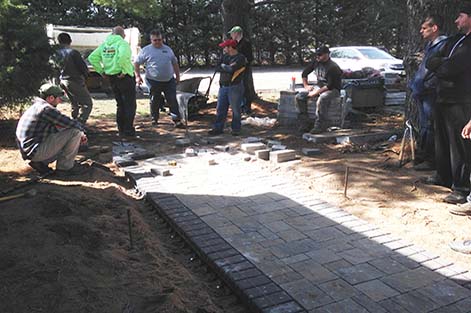 Concrete Pavers students step back to survey their progress on the paver walkway project.