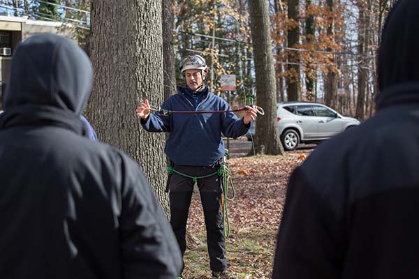 Instructor Mark Chisholm shows students tree climbing equipment during the field demonstration