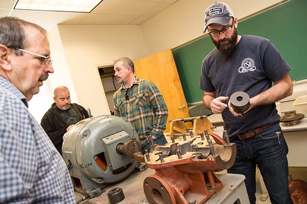 O & M of Pumps students examine pump parts during the hands-on session
