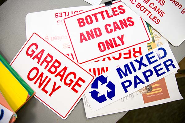 A variety of informational recycling signs on a table in the Improving Your Public Communication Skills class