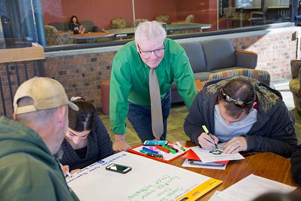 Improving Your Public Communication Skills instructor Bill Jamison observes students engaging in a group activity