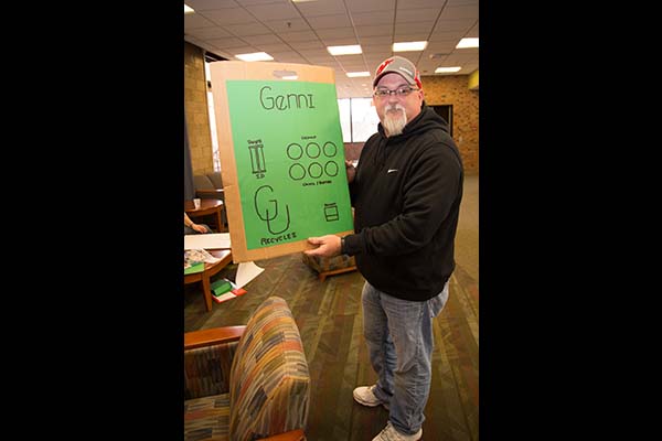 student shows off poster designed to encourage recycling of cans and bottles