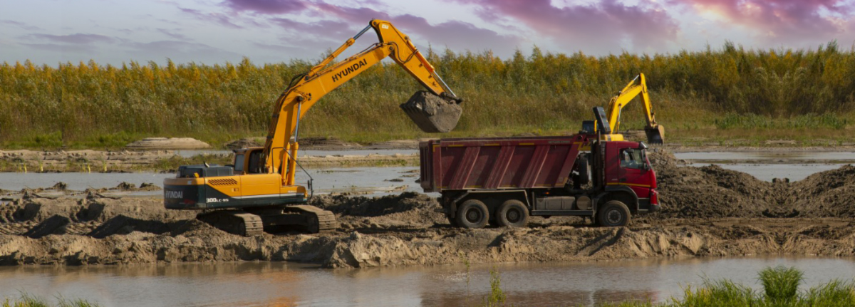 Excavator and dump truck at a wetland construction site