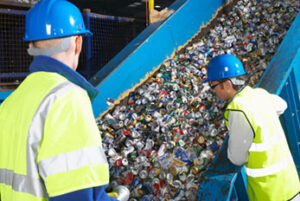Two recycling center workers monitoring conveyor belt of recycled cans