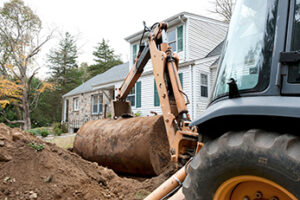 Construction vehicle removing heating oil storage tank from yard