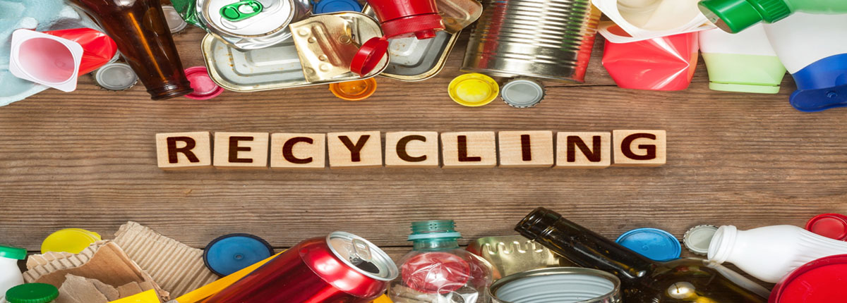 Wooden block letters spelling out the word Recycling surrounded by recyclable materials