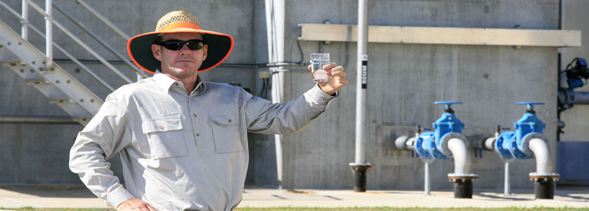 Man holding up glass of water at water treatment plant