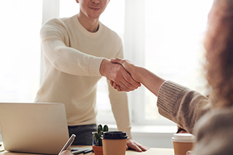 employer shaking hands across desk with employee