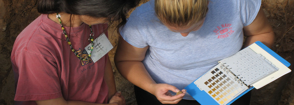 Two students compare soil samples to the Munsell Color Chart.
