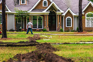 Freshly dug trenches for laying pipe to install a new irrigation system in a yard