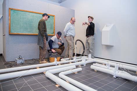 Instructor Bill Brodhead and students measure the air flow and pressure at different points in the radon mitigation system