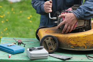 Man repairing lawn mower engine outside